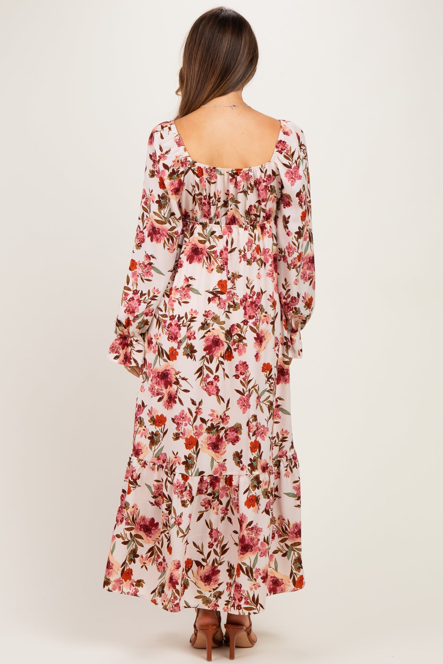 woman wearing a floral long sleeve maternity dress with a flowy fit and visible baby bump