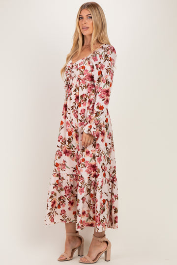 woman wearing a long pink floral maxi dress with long sleeves and a tiered skirt
