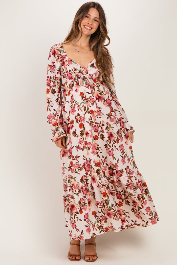 woman wearing a floral maxi maternity dress with a tie front and long sleeves, showcasing her baby bump