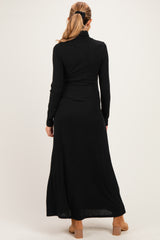 woman wearing a black long sleeve ribbed maternity dress, view from the back