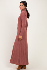 woman wearing a long dusty rose turtleneck maxi dress with long sleeves and a fitted silhouette