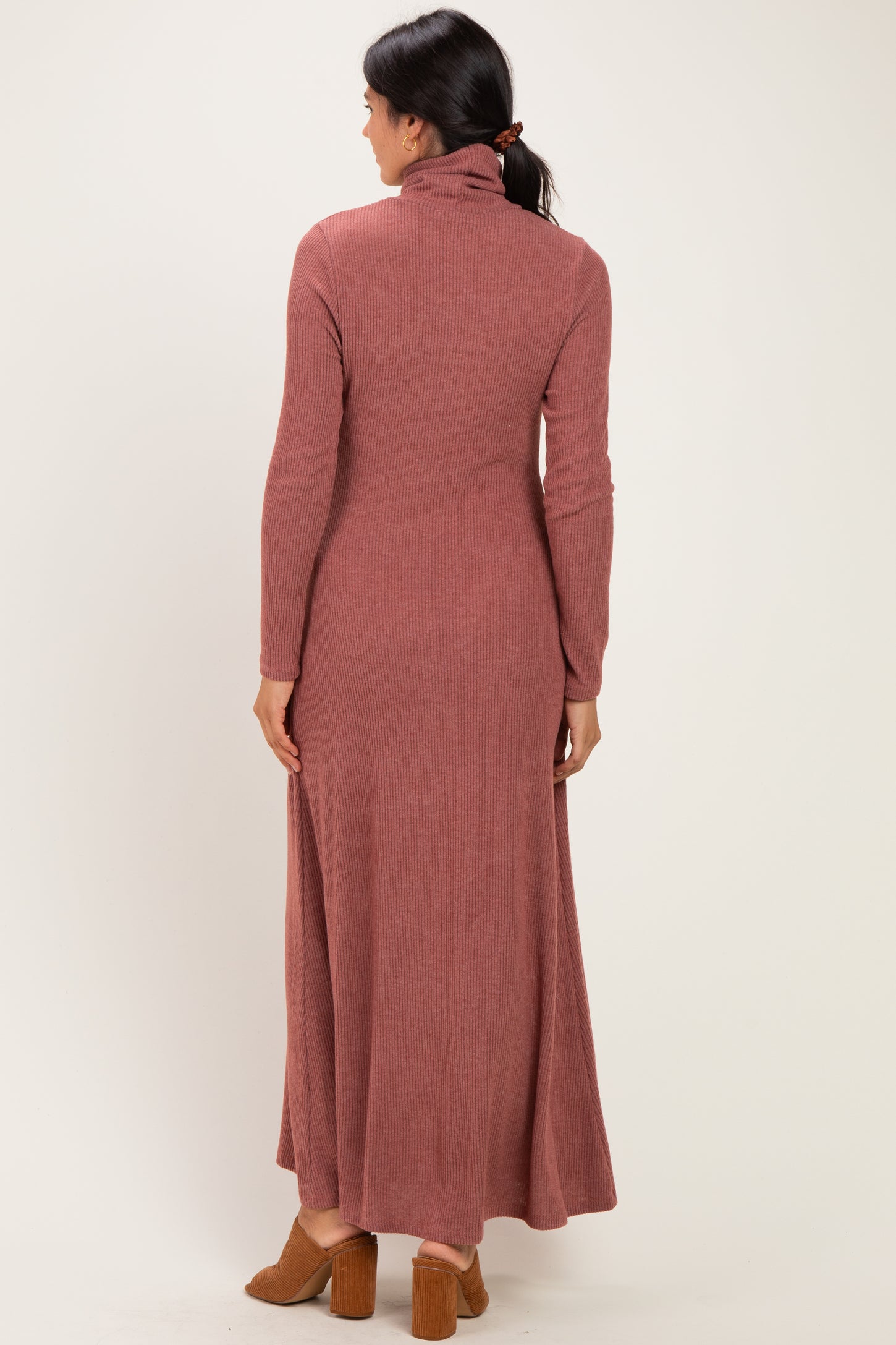 woman wearing a rust-colored long sleeve ribbed maxi dress with a turtleneck and open back