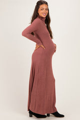woman wearing a rust long sleeve ribbed maxi dress with a fitted bodice and a flowing skirt, showing her baby bump