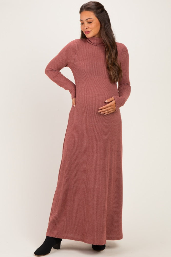 woman wearing a dusty rose long sleeve maternity dress with a turtleneck and side slits, holding her baby bump