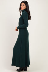 woman wearing a dark green long sleeve turtleneck maxi dress, standing sideways