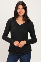 woman wearing a black long sleeve v-neck top with a gathered detail at the hem
