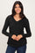 woman wearing a black long sleeve v-neck top with a gathered detail at the hem