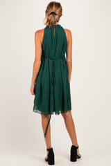 maternity wear in a dark green halter neck dress with a flowy silhouette and adjustable tie at the back