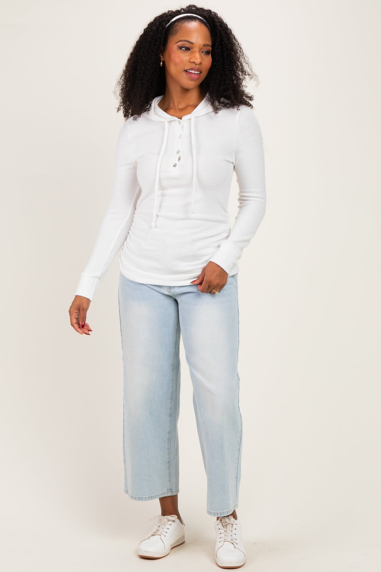 woman wearing a white long sleeve hoodie with buttons and light blue wide leg jeans
