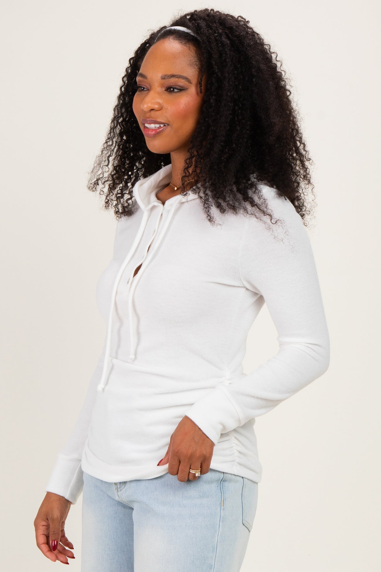woman wearing a white long sleeve hoodie with a drawstring while styled with light blue jeans