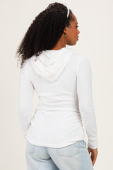 woman wearing a white long sleeve hoodie with a drawstring and gathered sides, facing away from the camera
