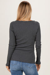 woman wearing a dark gray long sleeve top with a ruffled hem and back view, paired with blue jeans