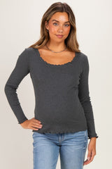 woman wearing a gray long sleeve maternity top with a scalloped neckline and holding her baby bump