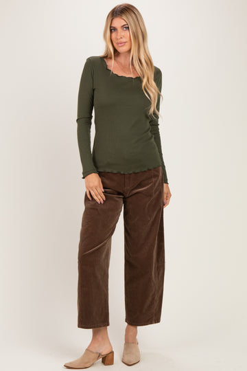 woman wearing an olive green long sleeve top with a scalloped neckline and brown wide-leg corduroy pants
