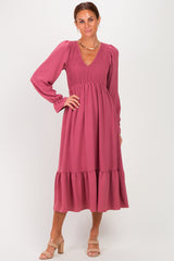 woman wearing a rose-colored long sleeve smocked dress with a tiered skirt and a V-neckline