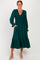 woman wearing a dark green long sleeve dress with smocked bodice and tiered skirt, posing with her hands in pockets