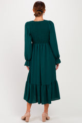 woman wearing a green long sleeve midi dress with smocked back and tiered skirt, seen from the back