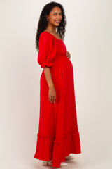 woman wearing a red off-the-shoulder maternity maxi dress with puff sleeves and ruffle hem, showing baby bump