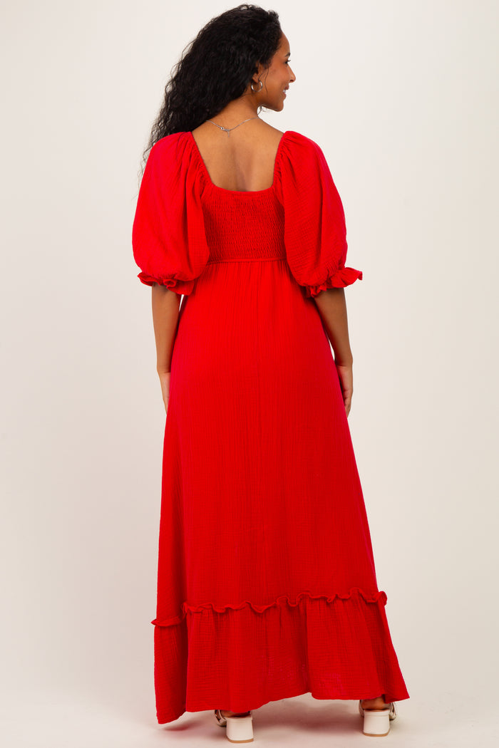 woman wearing a red maternity maxi dress with puff sleeves and ruffle hem, showing a baby bump from the back