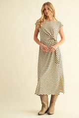 woman wearing a cream and black striped midi dress with a tie waist and high slit, paired with beige cowboy boots