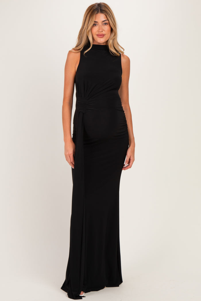 woman wearing a black sleeveless maternity gown with a side wrap detail and a visible baby bump