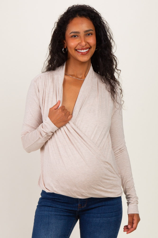 woman wearing a light beige maternity wrap top and showing her baby bump