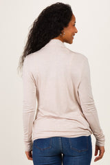 woman wearing a light pink long sleeve maternity top from the back, paired with blue jeans