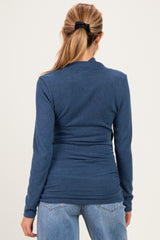 woman wearing a dark blue long sleeve maternity top, seen from the back, paired with light wash jeans