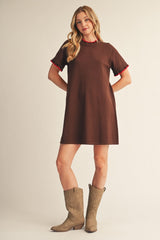 woman wearing a brown short sleeve dress with red trim and knee-high brown cowboy boots