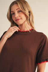woman wearing a brown short sleeve sweater with red ruffled trim around the neckline and sleeves