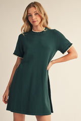 woman wearing a dark green short sleeve dress with ruffle details on the sleeves
