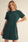 woman wearing a dark green short sleeve dress with ruffle details on the sleeves