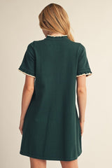 back view of a woman wearing a dark green short sleeve dress with scalloped detail on the sleeves