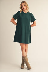 woman wearing a green short sleeve dress with scalloped trim and brown cowboy boots