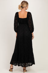 woman wearing a black lace maxi dress with long sleeves and a ruffled hem, viewed from the back
