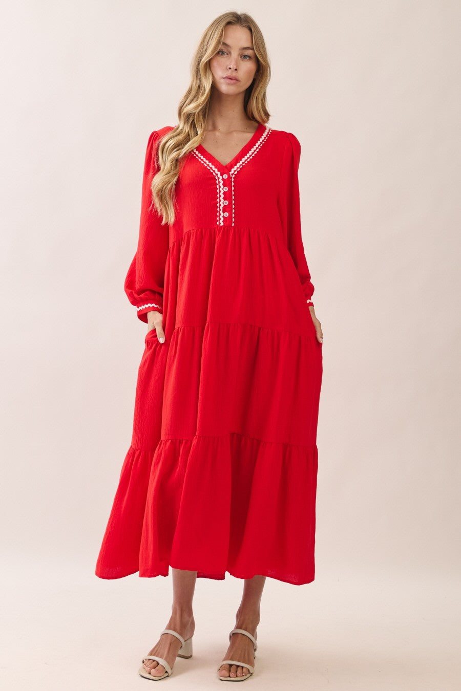 woman wearing a red tiered maxi dress with a buttoned v-neck and long sleeves, featuring pockets and a relaxed fit