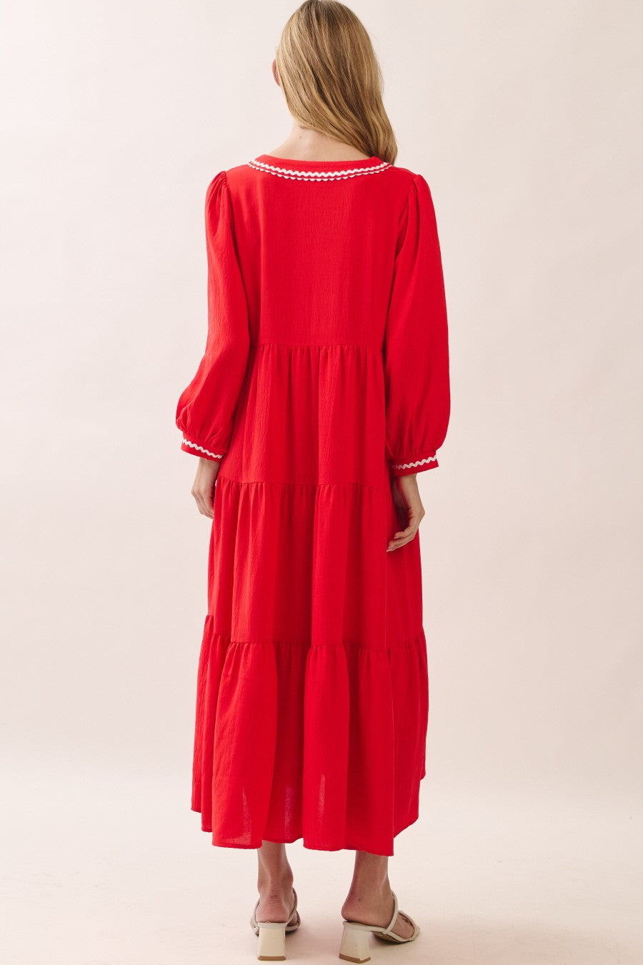 woman wearing a red tiered maxi dress with long sleeves and white trim детали на спине