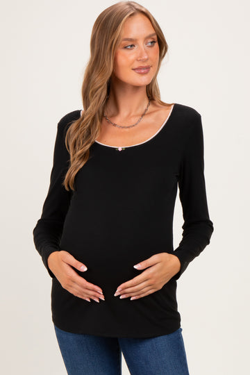 woman wearing a black long sleeve maternity top with a scoop neckline and holding her baby bump
