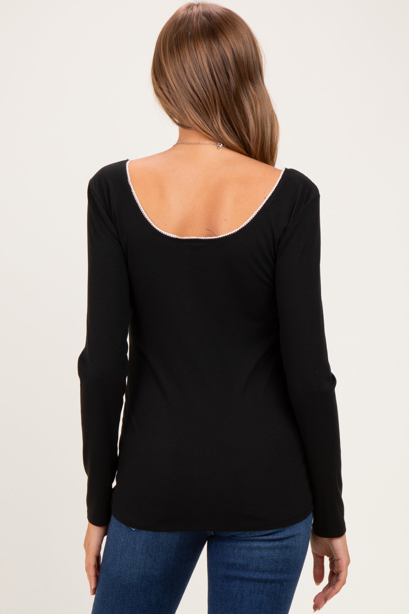 woman wearing a black long sleeve maternity top with a scoop back and stylish ribbed texture