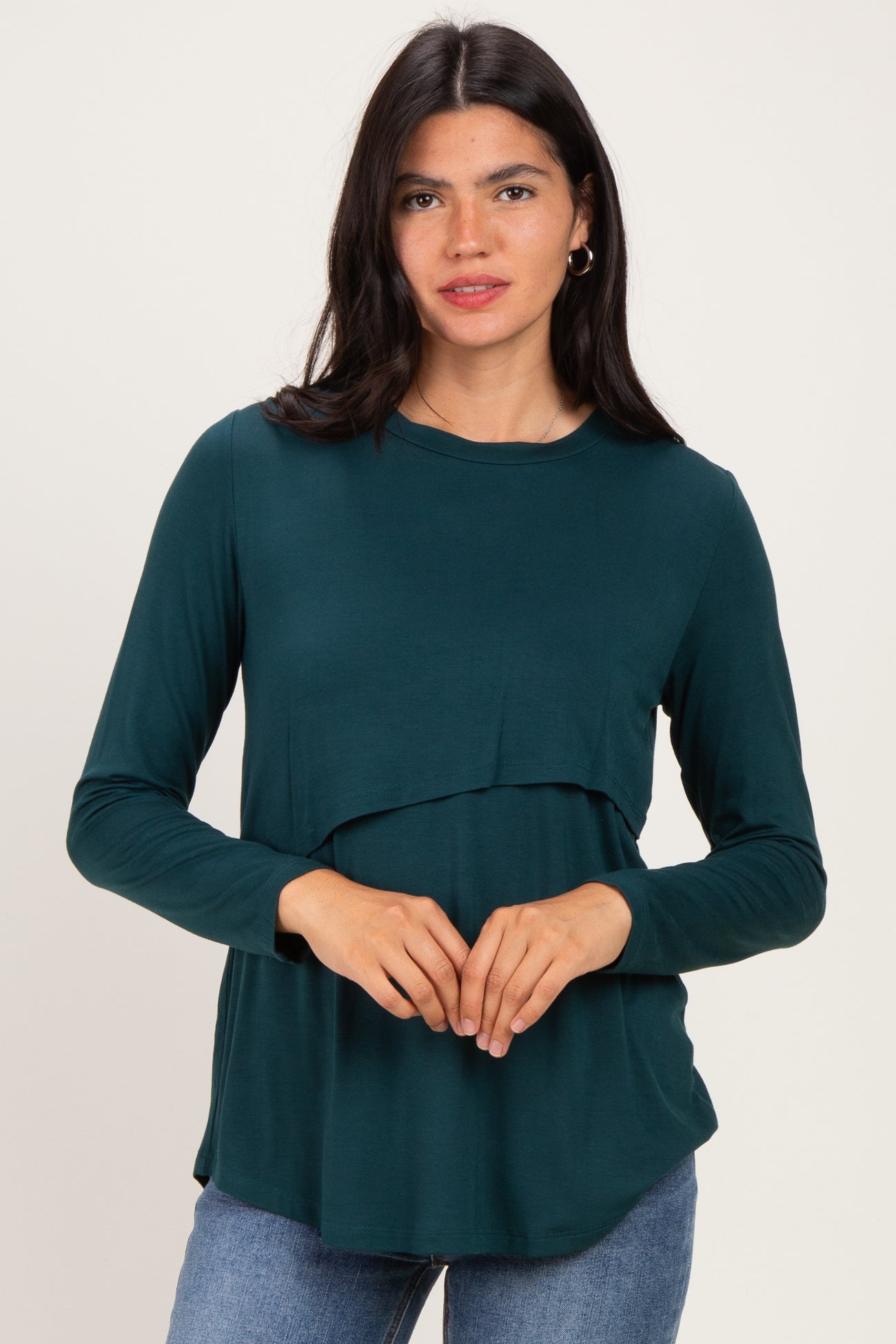 woman wearing a dark green long sleeve layered top with a relaxed fit and rounded hem