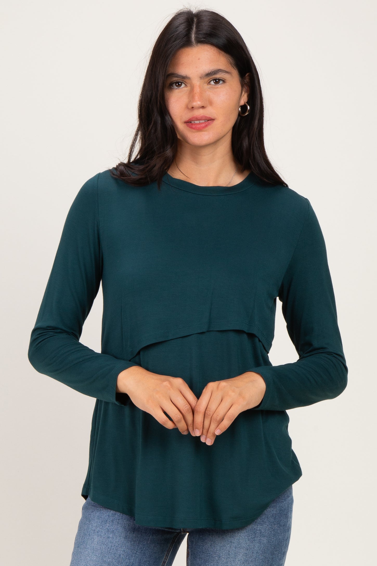 woman wearing a dark green long sleeve layered top with a relaxed fit and rounded hem