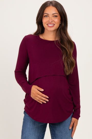 woman wearing a burgundy long sleeve maternity top with a rounded hem and a visible baby bump