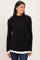 woman wearing a black ribbed long sleeve top with a white layered hem and smiling