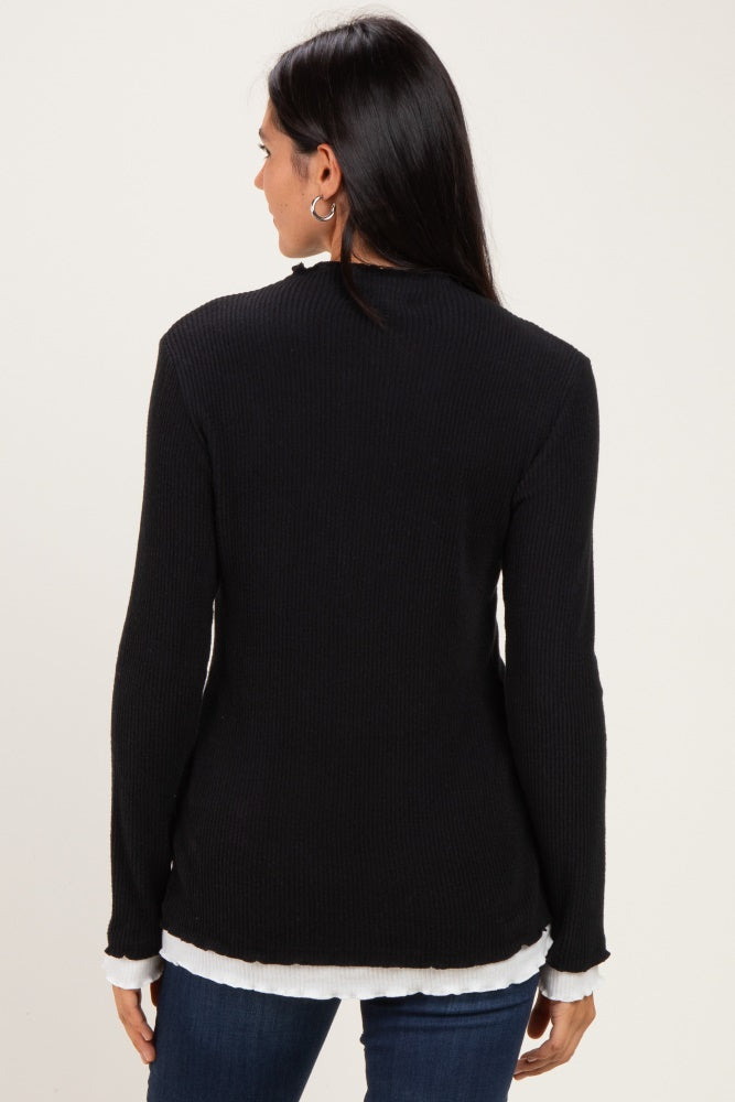 woman wearing a black ribbed long sleeve top with a white layered hem, seen from the back