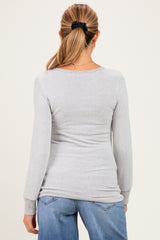 woman wearing a light grey maternity long sleeve top, viewed from the back, paired with blue jeans