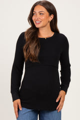 woman wearing a black long sleeve maternity top with a fitted bodice and relaxed hemline, smiling