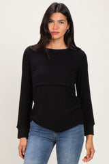 woman wearing a black long sleeve top with a layered design and relaxed fit, paired with blue jeans