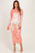woman wearing a coral and white long sleeve lace maternity dress with intricate floral patterns and a fitted silhouette