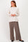 woman wearing a cream oversized sweater and brown wide-leg pants, standing with a relaxed pose