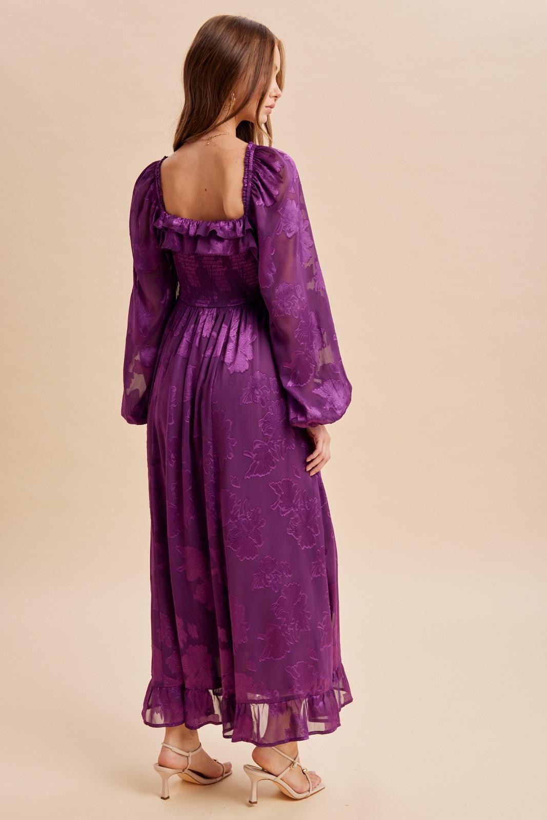 woman wearing a purple floral maxi dress with puff sleeves and a smocked back, shown from the back
